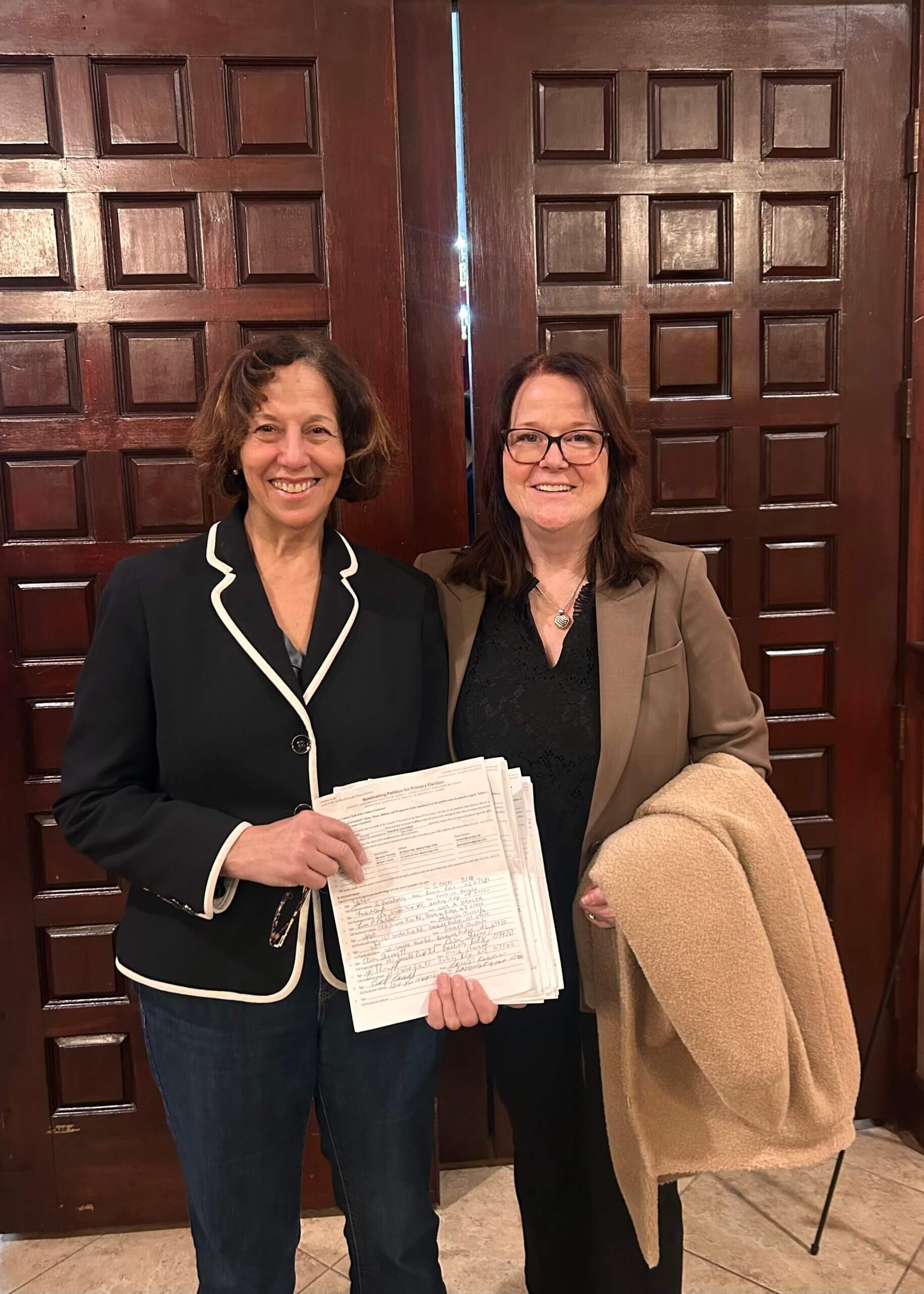 Ana Duarte McCarthy and Joan Bannan standing in front of wooden double doors